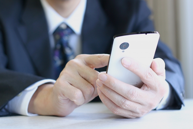 男性が携帯を扱っている写真